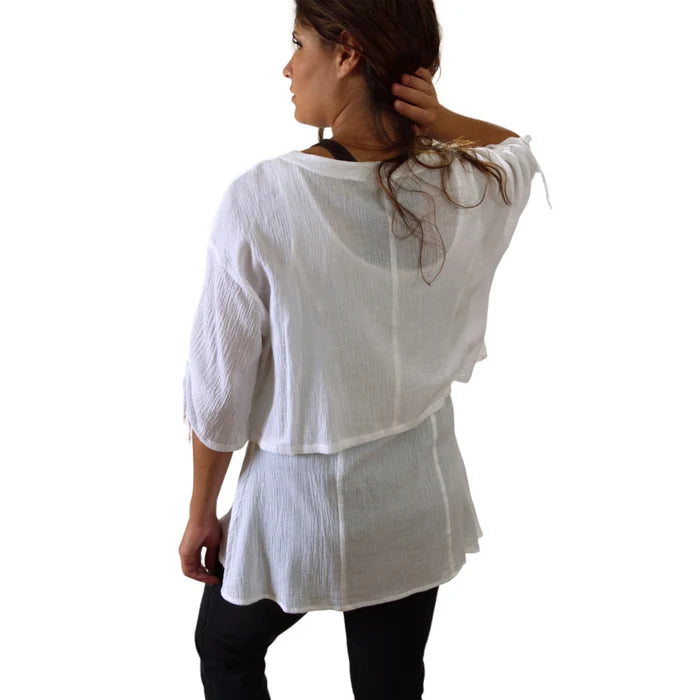 Woman wearing a white layered top against a white background