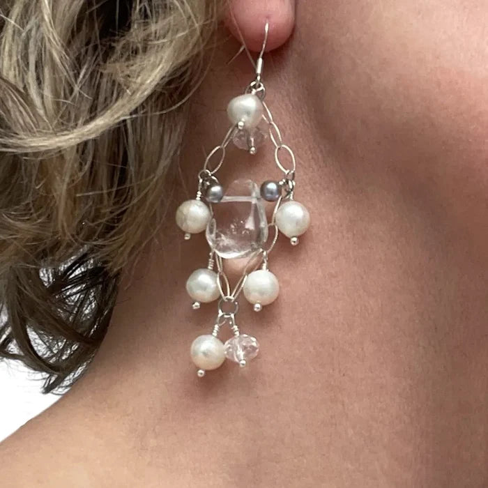 Close-up of a woman wearing a silver earring with pearls and clear beads.
